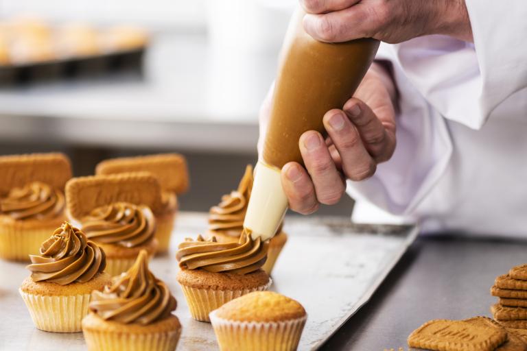 Baker piping Biscoff cupcakes